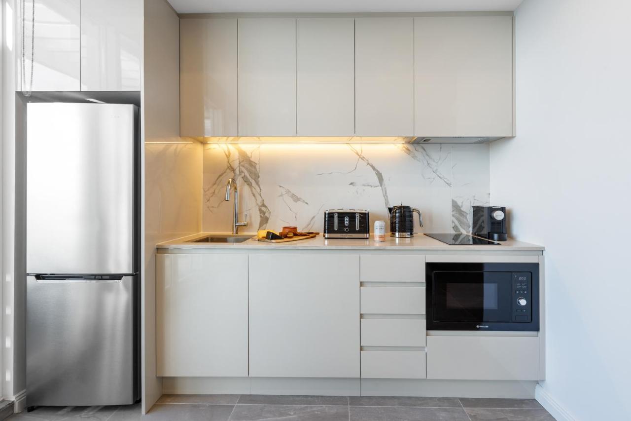 Meriton Suites Bondi Junction Sydney Kültér fotó The photo shows a modern kitchen featuring a sleek design. It includes light-colored cabinetry with a smooth finish and upper cabinets that blend seamlessly with the wall. The countertop is made of a light stone, complementing the overall aesthetic. 