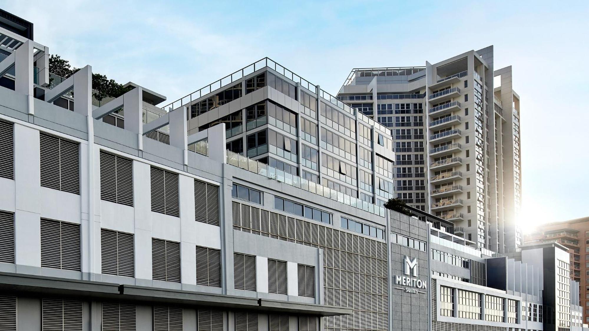 Meriton Suites Bondi Junction Sydney Kültér fotó The image shows a modern urban building or complex. The structure features a combination of glass and concrete elements, showcasing contemporary architectural design. The foreground has a lower section that appears to be a podium or base with a textu